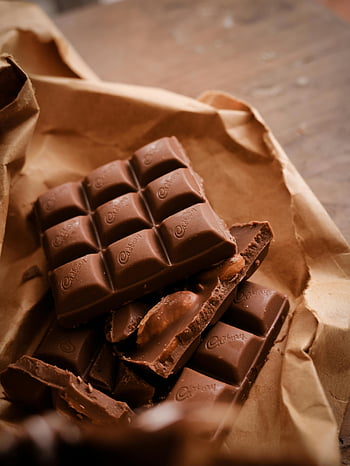 chocolate bar, close-up photo, rustic wrapping paper, indulgence imagery, chocolate pieces, Cadbury chocolate, sweet treats, dessert photography, food photography, chocolate indulgence, chocolate close-up