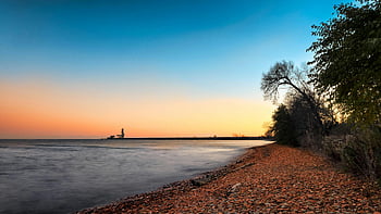 sunset, Lake Ontario, tranquil shoreline, distant lighthouse, Mississauga, Canada, blue sky, trees on shoreline, peaceful scene, natural beauty, waterfront view