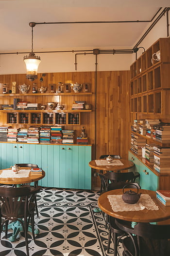Braune Holzbratensets, Warmes Café, Vintage-Dekor, Holzwände, Bücherregale, gemütliches Interieur, gemusterter Boden, Hängelampe, Teekannen, Atmosphäre einladende, Retro-Stil