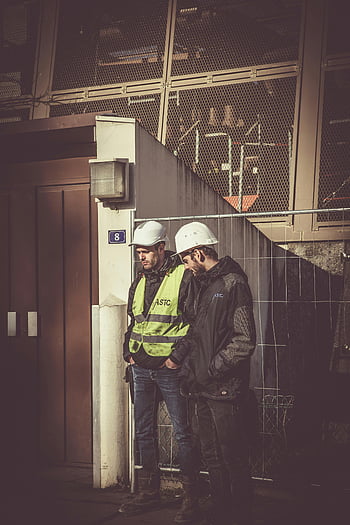 construction workers, white hard hat, safety gear, building site, outdoor work, ASTC, safety vest, industrial setting, two men, focused work, construction site