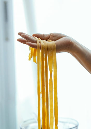 handmade spaghetti, fresh pasta, kitchen setting, close-up, long spaghetti, fresh handmade, pasta preparation, spaghetti strands, pasta making, kitchen scene, spaghetti noodles