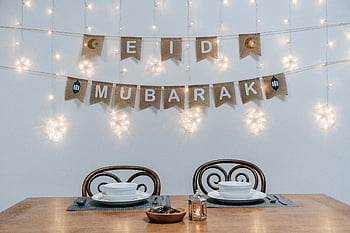 Eid Mubarak, string lights, festive ambiance, white ceramic plates, brown wooden table, dining table, decorations, Eid decorations, table setting, festive table