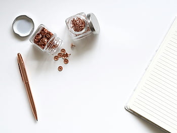 thumbtacks, clear glass containers, white surface, minimalist flat lay, office supplies, notebook, pen, jars of clips, white background, copper thumbtacks, copper pen