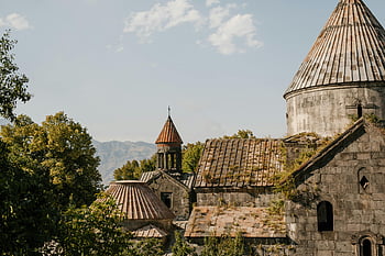 Armenian monastery, historic church, cross on roof, serene view, surrounded by nature, medieval architecture, ancient building, religious site, stone structure, natural landscape, mountain backdrop