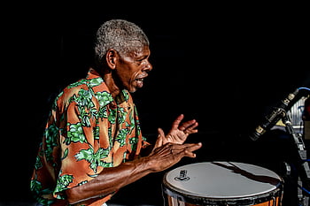 elderly African American, percussionist, conga drum, outdoor performance, energetic playing, musical performance, African American musician, outdoor music, conga player, senior musician, live music