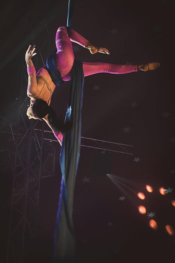 woman acrobat, acrobatic stunts, silk ribbons, upside down, dramatic lighting, skilled acrobat, aerial performance, circus act, aerial silk, performance art, acrobatic skills