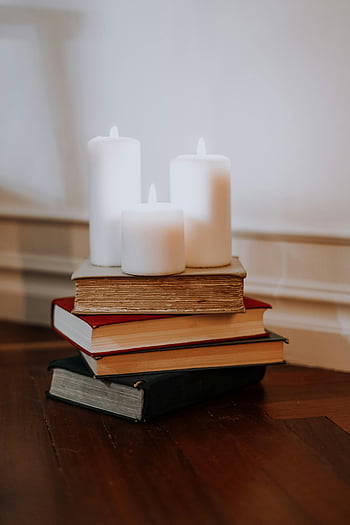 Свещи за книги, купчина книги, запалиха свещи, Уютна атмосфера, дървена повърхност, Настройка на закрито, бели свещи, реколта книги, топло осветление, домашен декор, Четене на кътче