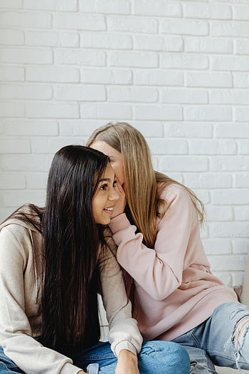Ženské teenagery, neformální oblečení, šeptá, usmívající se, uvnitř, bílá cihlová zeď, konverzace, dospívající dívky, příležitostné oblečení, Vnitřní nastavení, Přátelská interakce