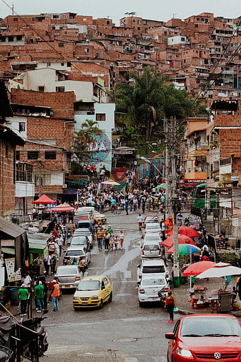Medellin, Antioquia, Colombia, mountain houses, vibrant street scene, bustling activity, neighborhood architecture, street market, colorful umbrellas, city life, urban landscape