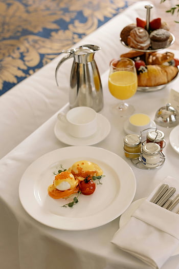 hotel breakfast, poached eggs, pastries, orange juice, luxury breakfast, indoor breakfast, elegant breakfast, breakfast service, breakfast table, breakfast spread, breakfast arrangement