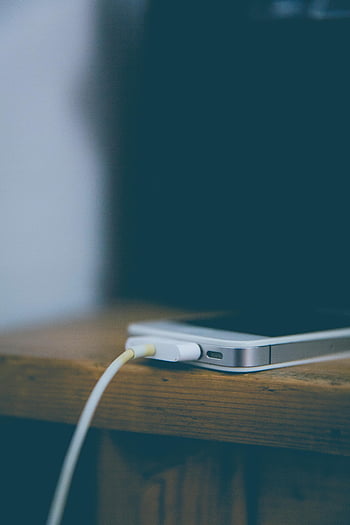 stříbrný iphone 6, hnědý dřevěný stůl, Nabíjení smartphonu, dřevěný stůl, Nastavení kanceláře, detail, technologie, lavice, nabíjecí kabel, kancelářský stůl, telefon