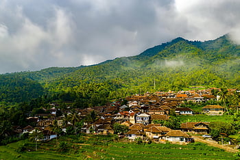 aerial photography, house near mountain, picturesque village, lush green hills, Majasari, Indonesia, rural landscape, mountain view, traditional houses, tropical scenery, cloudy sky