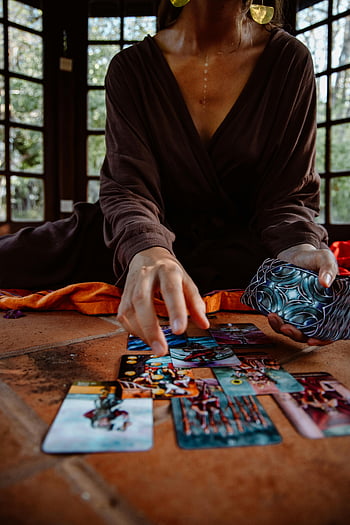 tarot cards, person in robe, tarot card reading, wooden floor, mystical ambiance, tarot reading, mystical setting, tarot cards spread, person performing tarot, tarot session, mystical tarot