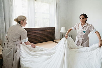 hotel housekeepers, changing sheets, hotel room, sunlit room, professional cleaning, hospitality, bed sheets, hotel staff, room service, housekeeping duties, hotel maintenance