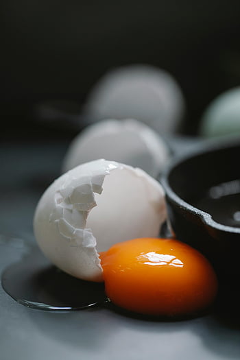 uovo incrinato, tuorlo luminoso, superficie scura, concetti culinari, concetti gastronomici, tavolo nero, guscio d'uovo, fotografia di cibo, alto contrasto, tuorlo d'uovo, guscio d'uovo rotto