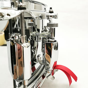 chrome drum hardware, shiny chrome parts, drum hardware, drum set parts, red ribbon accent, musical instruments, drum accessories, drum hardware components, drum part close-up