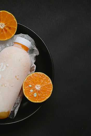 suco de laranja fria, garrafa fosca, fatias de laranja vibrantes, suco cítrico refrescante, fundo preto, Tigela de gelo, bebida cítrica, metades de laranja, suco gelado, vidro fosco, bebida refrescante