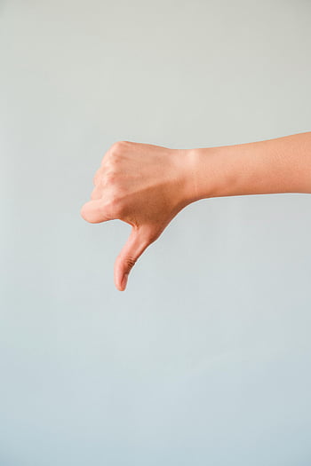 thumbs down, hand gesture, close-up, light blue backdrop, negative sign, disapproval, human hand, body language, non-verbal communication, dislike, gesture