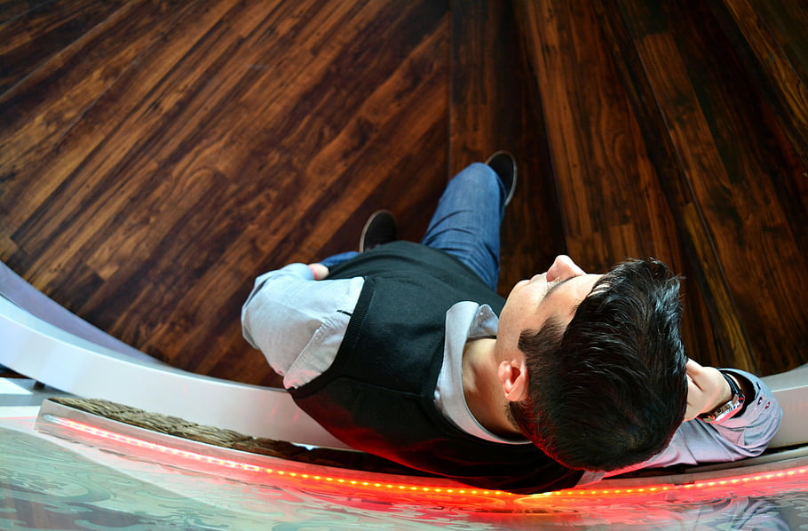 man, selfie, spiral staircase, wooden flooring, indoor, relaxing, overhead view, casual attire, red lighting, modern interior, comfortable pose