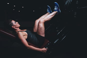 donna, macchina leg press, focalizzata, esercizio, palestra debolmente illuminata, fitness, allenarsi, formazione, Salute, forza, equipaggiamento da palestra