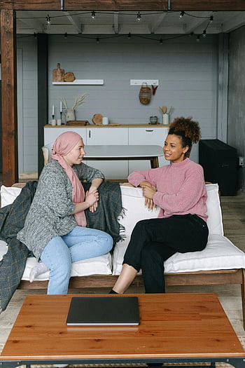 friends chatting, sitting on couch, heartfelt conversation, support and friendship, two women, cozy living room, casual conversation, emotional connection, home setting, comfortable couch, relaxed atmosphere