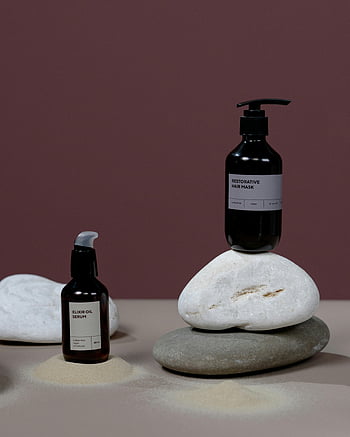 organic haircare products, labeled bottles, stones, studio shot, minimalistic design, elixir oil serum, restorative hair mask, natural beauty, product photography, hair care, stone display