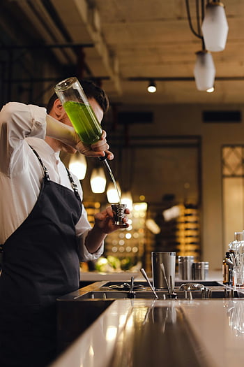 barista, miscelazione di bevande, cocktail verde vibrante, barman, bar alla moda, versare cocktail, bancone da bar, barman abile, bar elegante, preparazione di bevande, cocktail contemporaneo