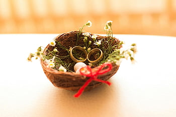 wedding rings, gold-colored wedding band, floral basket, love and commitment, selective focus photography, golden wedding rings, symbolizing love, commitment, wedding band, floral arrangement, red ribbon