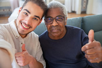 elderly man, young man, smiling, thumbs up, friendship, care, home, multi-generational, positive emotions, indoor setting, casual attire