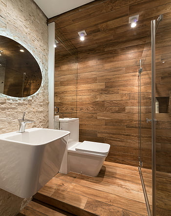 Současná toaleta, Kreativní dřez, moderní koupelna, dřevěné stěny, Elegantní sanitární příslušenství, Relaxační design, kulaté zrcadlo, Skleněná sprcha, minimalistický design, teplé osvětlení, kamenná zeď