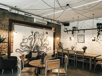 Šedá chobotnice, Okouzlující restaurace, dřevěný nábytek, Octopusová nástěnná malba, Útulná atmosféra, Umělecký interiér, cihlové zdi, závěsná světla, jídelní stoly, židle, váza květy