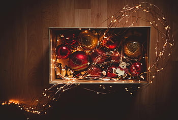Christmas ornaments, red baubles, yellow baubles, string lights, wooden surface, top-down view, vibrant ornaments, festive decorations, holiday decor, Christmas lights, box of ornaments