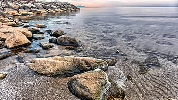 Mississauga shoreline, gray and blue seashore, peaceful shoreline, calm water, rocks, dusk, Ontario, beach scene, natural landscape, serene waters, evening view
