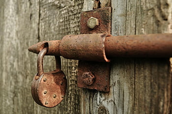 brown metal padlock, rusty padlock, weathered wooden door, close-up view, metal latch, rusted lock, old padlock, vintage lock, metal hardware, outdoor lock, aged padlock