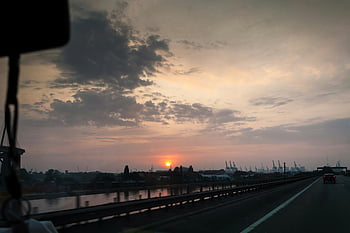 highway, sunset, industrial skyline, dramatic clouds, car, road, night time, bridge, water, cityscape, evening
