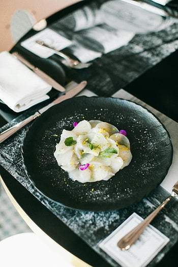 sliced radishes, elegant plate, sashimi, garnished greens, flowers, Asian cuisine, black plate, table setting, fine dining, food presentation, culinary art