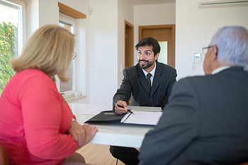 real estate agent, senior couple, office setting, real estate discussion, real estate deal, senior clients, real estate meeting, professional meeting, real estate consultation, real estate office, real estate transaction