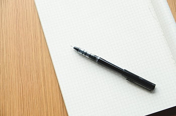 black ballpoint pen, white ruled paper, grid notebook, writing, design, black pen, open notebook, desk, stationery, office supplies, study tools