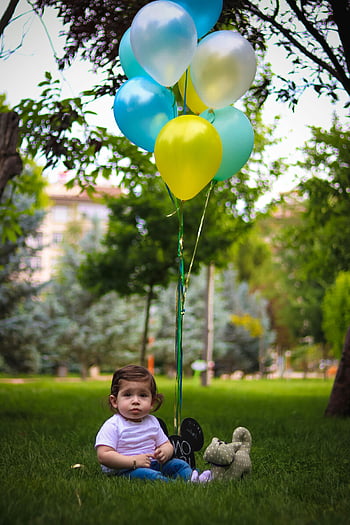 baby, blue balloons, yellow balloons, cute baby, grass, scenic park, colorful balloons, outdoor setting, baby sitting, park setting, baby photography