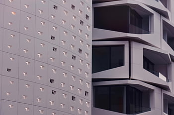 white high-rise building, modern architecture, intricate facade design, close-up building, unique building design, urban architecture, contemporary building, high-rise structure, architectural details, modern high-rise, building exterior