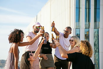 joyful friends, diverse group, clinking beer bottles, rooftop party, outdoor gathering, fun celebration, toasting friends, beer toast, rooftop fun, diverse celebration, outdoor friends
