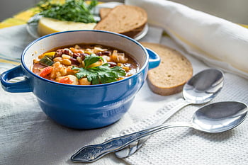 vegetable soup, blue ceramic bowl, bread slices, cozy table setting, silver spoons, colorful soup, table setting, ceramic bowl, vegetable broth, cozy meal, silverware