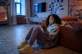 teini-ikäinen tyttö, istuu lattialla, älypuhelimen käyttäminen, viihtyisä huone, rento ympäristö, älypuhelimen käyttö, sisä, Rento asu, keltaiset lenkkarit, kotiympäristö, kuulokkeet