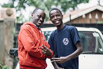 smiling young men, peace signs, outdoors, happiness, friendship, posing for camera, outdoor photo, two men, casual clothing, natural setting, cheerful expressions