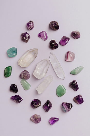 colorful semiprecious stones, polished gemstones, vibrant colors, gray tabletop, jewelry store, white surface, amethyst, quartz, fluorite, crystals, arrangement