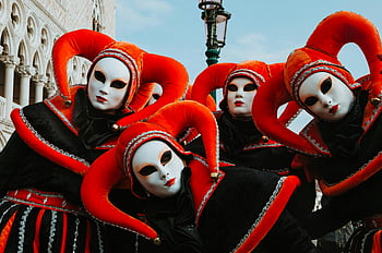 Venice Carnival, vibrant costumes, carnival masks, Venetian tradition, artistry, jester costumes, white masks, red hats, group photo, festive attire, cultural event