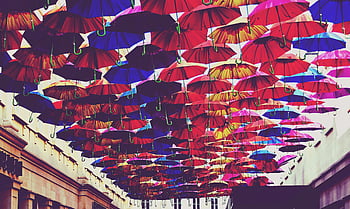 colorful umbrellas, overhead display, UK city street, red umbrellas, blue umbrellas, orange umbrellas, street art, urban decoration, vibrant colors, public art, hanging umbrellas