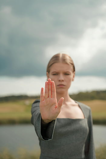 woman, stop gesture, hand gesture, cloudy sky, outdoor, close-up, young woman, stop sign, body language, nature background, overcast weather