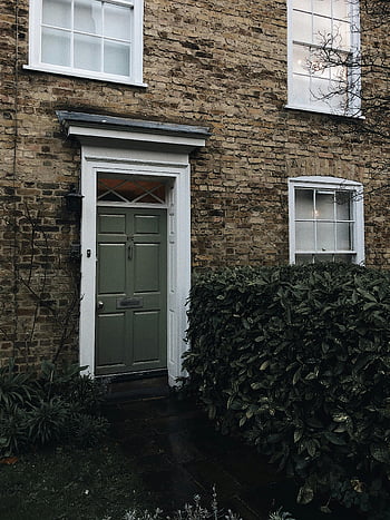 closed door, house entrance, classic English townhouse, green door, brick facade, charming entrance, white windows, front door, residential building, traditional architecture, outdoor plants