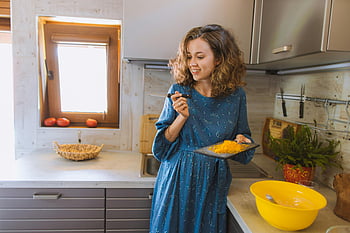 woman in blue dress, smiling woman, preparing food, kitchen, holding knife, cutting board, food preparation, kitchen scene, woman cooking, blue long sleeve dress, kitchen activity